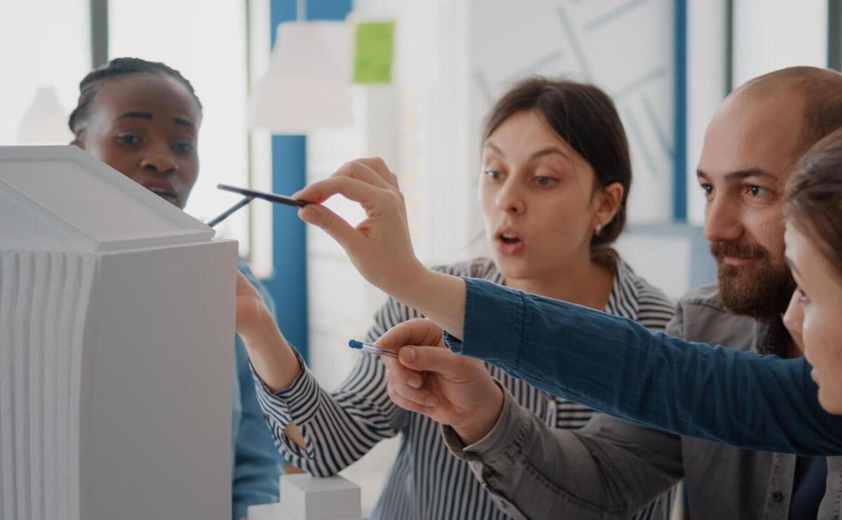 Close up of workmates analyzing building model and maquette on table to design construction. group of diverse colleagues working on architecture project for structure and development.